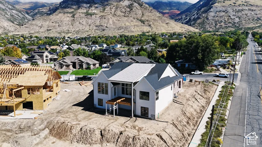 New construction home featuring a white exterior, dark shingle roof, and a rear balcony with a pergola