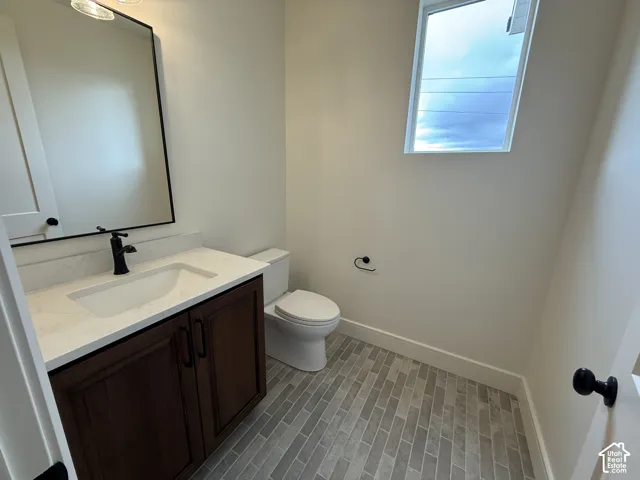 Dark wood-finish vanity with a stone-surface countertop, rectangular undermount sink, matte black faucet, and vertical-pattern tile flooring
