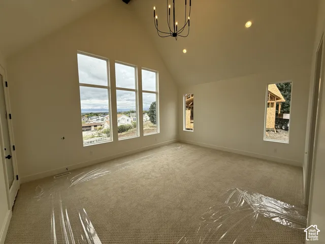Primary Bedroom with Vaulted ceilings, expansive windows, wall-to-wall carpeting, and a modern tiered chandelier