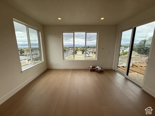 Light-filled interior featuring wood-finish flooring, recessed lighting, expansive multi-pane windows, and a sliding glass door providing access to an unfinished exterior deck