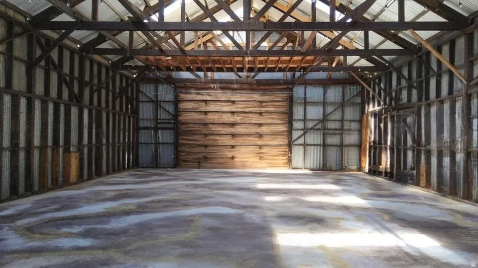Spacious interior featuring a high exposed timber beam ceiling, corrugated metal wall panels, and a concrete floor