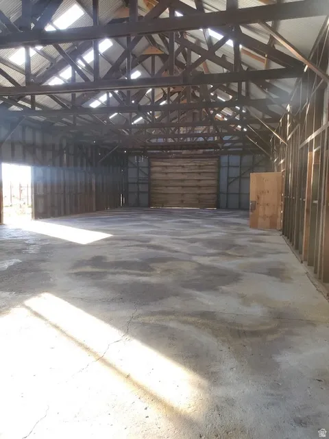 Spacious interior featuring exposed wooden rafters, corrugated metal roofing with skylights, and a large wooden sliding door
