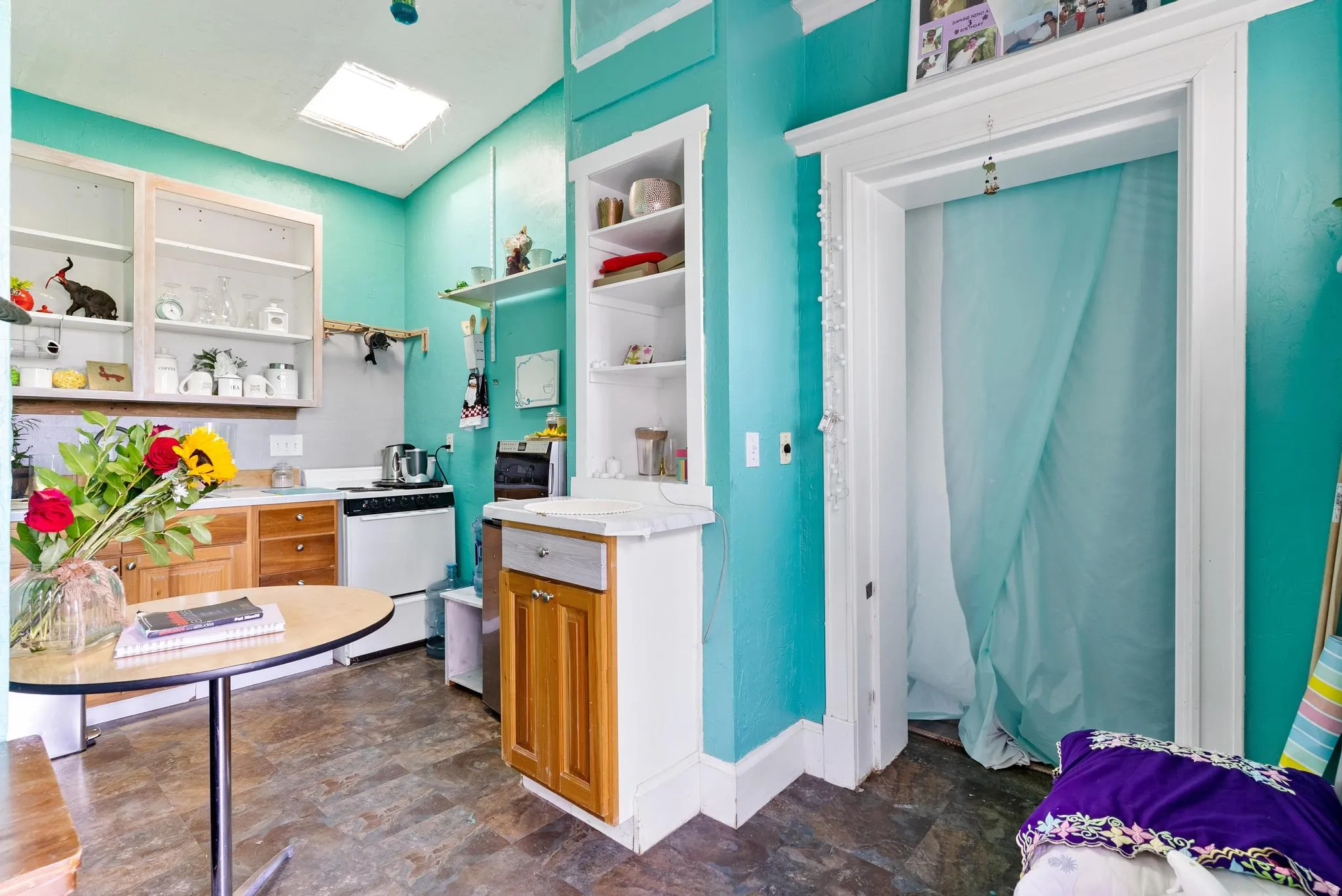 Kitchen space featuring wood-finish lower cabinetry, white upper cabinetry with glass inserts, and a skylight
