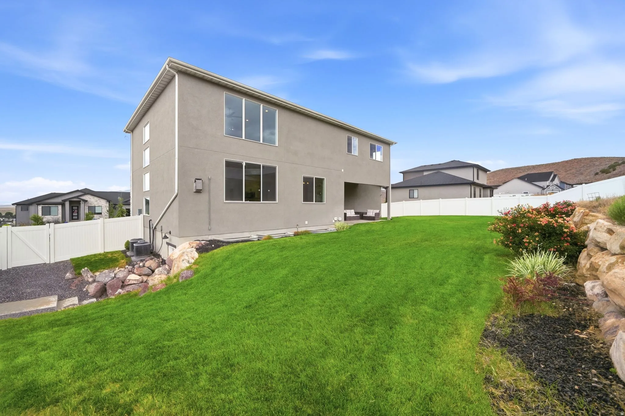 Expansive lawn with a sloped landscape, rock features, and mature shrubs