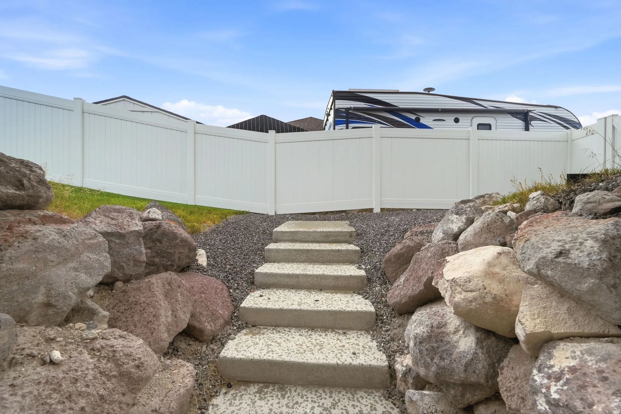 Hardscaped exterior with concrete steps, gravel paths, and a rock retaining wall