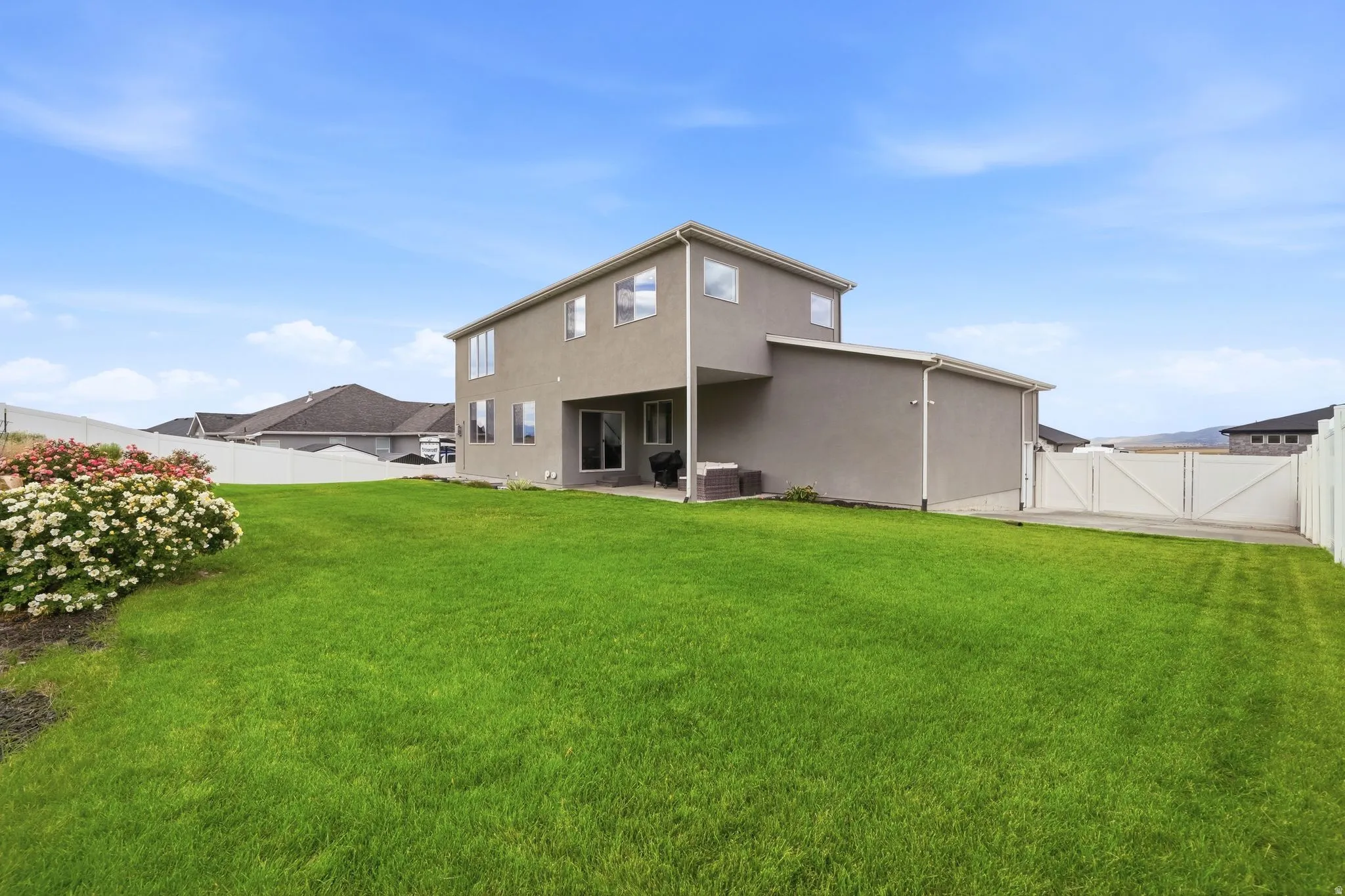 Spacious backyard featuring a manicured lawn, a flowering shrub, and a privacy fence