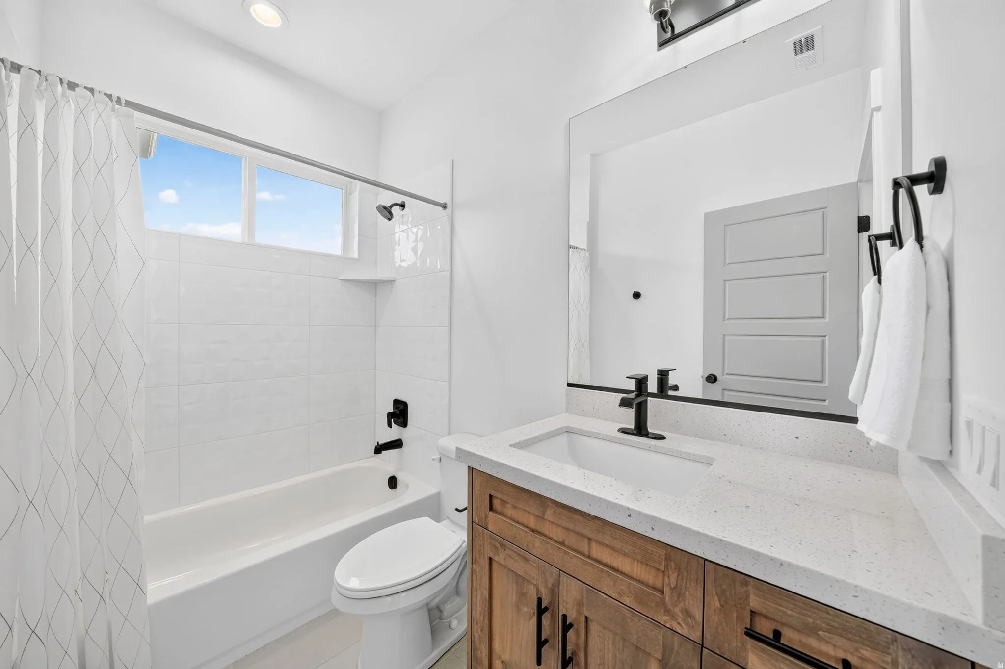 Modern bathroom featuring a wood-finish vanity with a light-toned countertop and an undermount sink