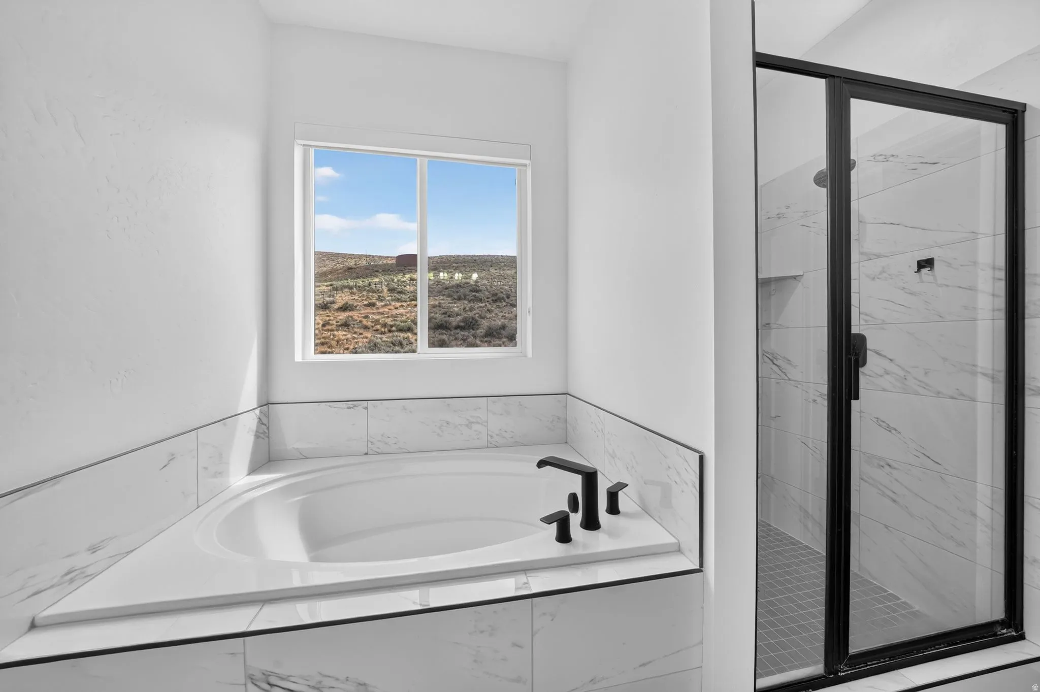 Built-in soaking tub with matte black fixtures, surrounded by marble-look tile