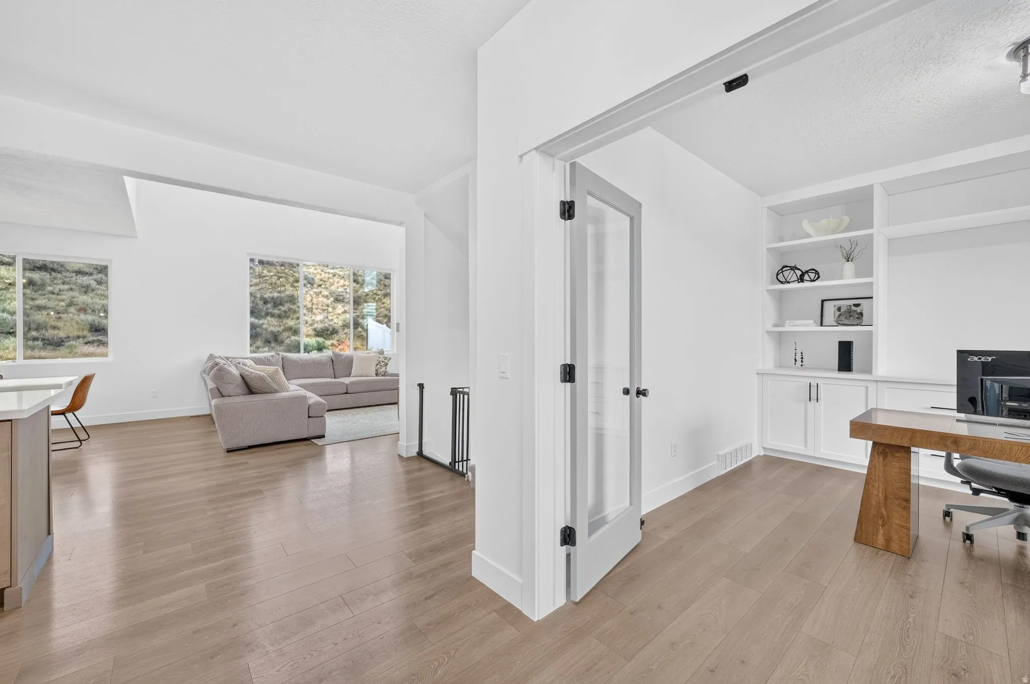 Dedicated office space featuring custom built-in shelving and cabinetry, wood-finish flooring, and a glass-paneled door