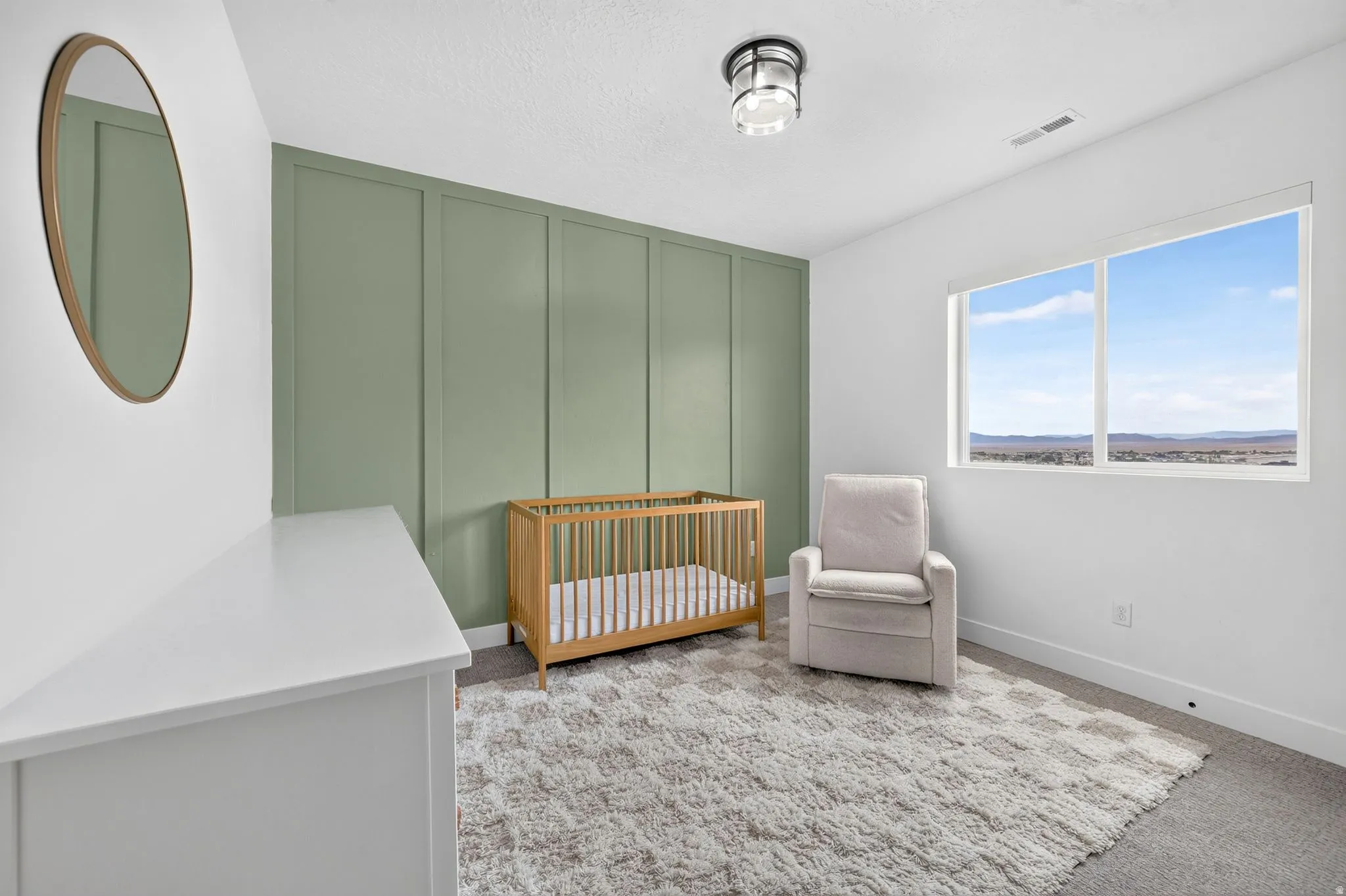 Second-floor bedroom featuring a green accent wall with vertical paneling, white walls, and a large window
