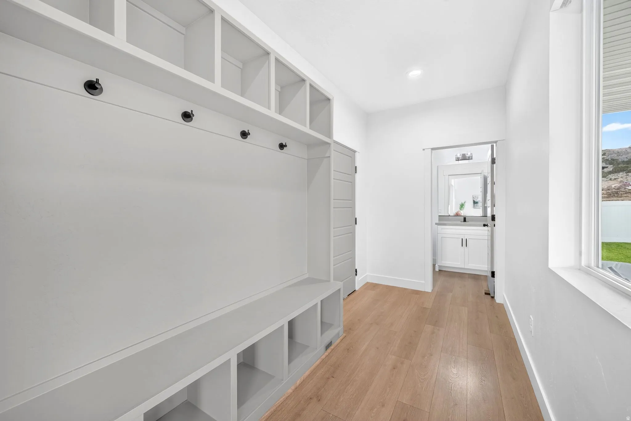 Integrated built-in storage system featuring open shelving, a bench with cubbies, and wall-mounted hooks