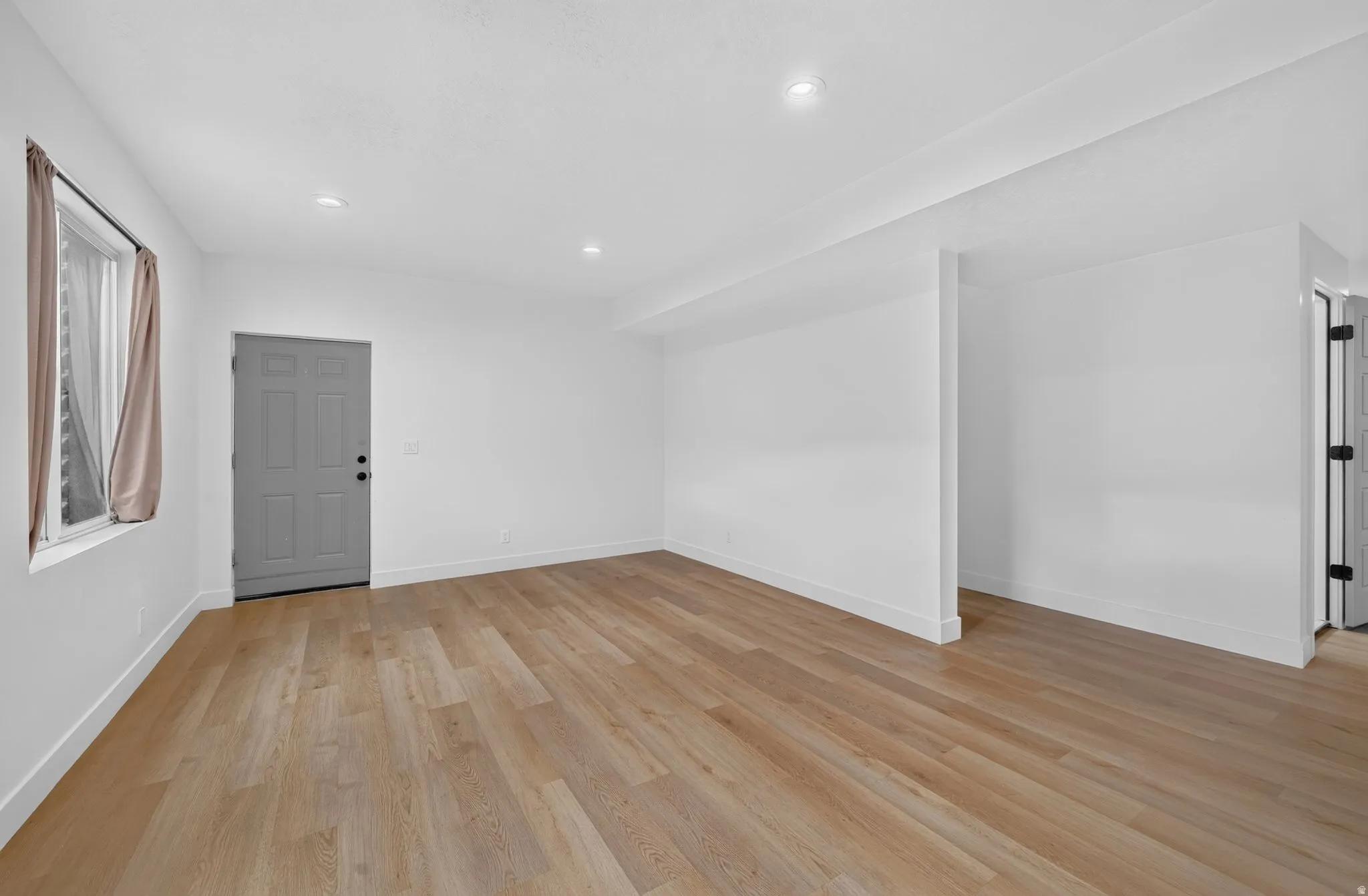 Neutral-toned wood-finish flooring complements the bright white walls and recessed lighting