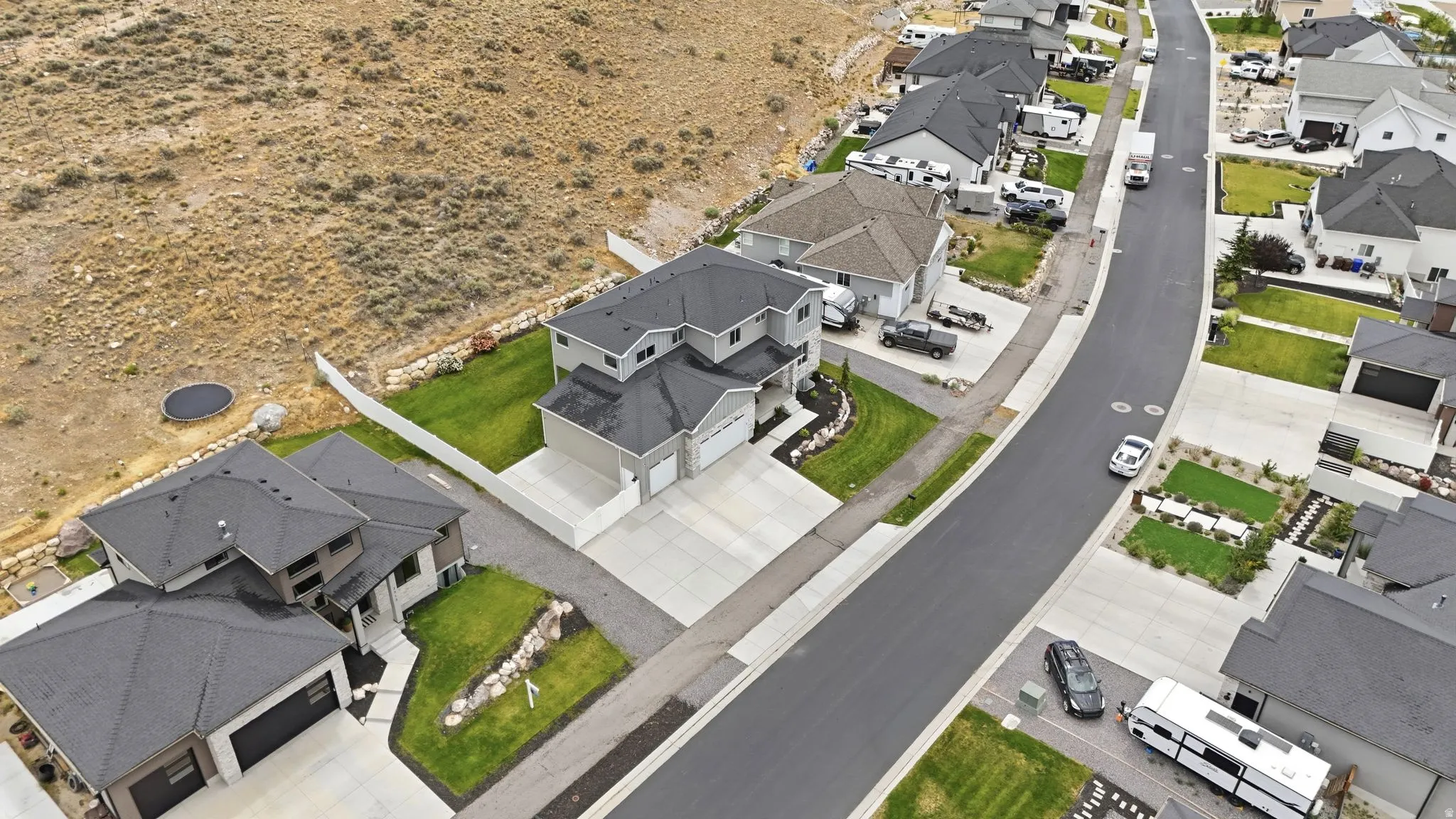 Contemporary two-story residence featuring a two-car garage, concrete driveway, and landscaped front yard with green lawn and decorative rock accents