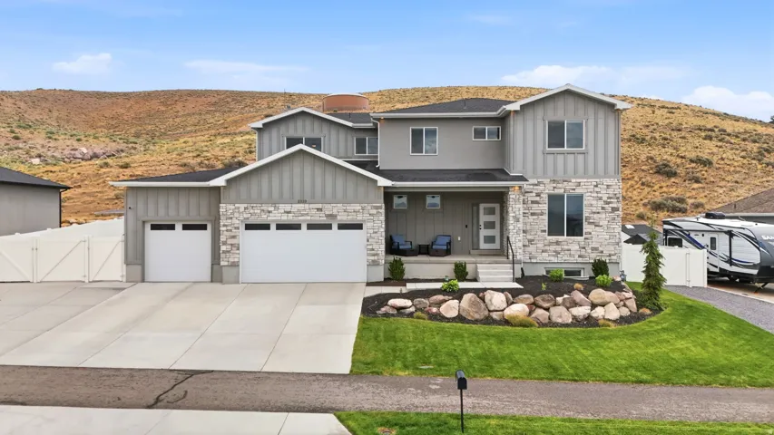 Contemporary two-story residence featuring a mixed-material facade with stone veneer and vertical siding accents