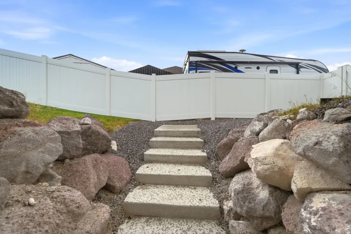 Hardscaped exterior with concrete steps, gravel paths, and a rock retaining wall
