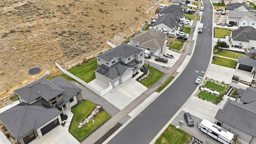 Contemporary two-story residence featuring a two-car garage, concrete driveway, and landscaped front yard with green lawn and decorative rock accents