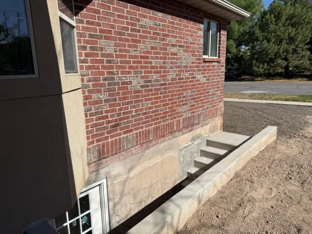 Red brick exterior with a concrete basement entry and steps