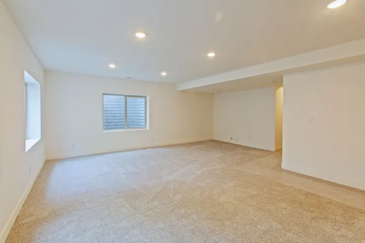 Spacious room featuring neutral carpeting, recessed lighting, white baseboards, and two windows