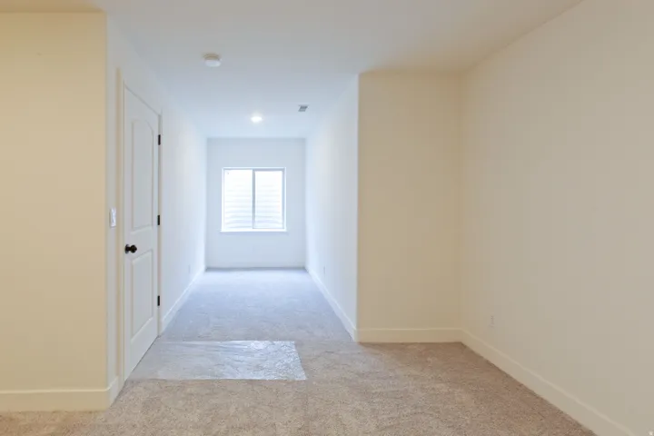 Carpeted room with a white door, recessed lighting, and a horizontal window with blinds