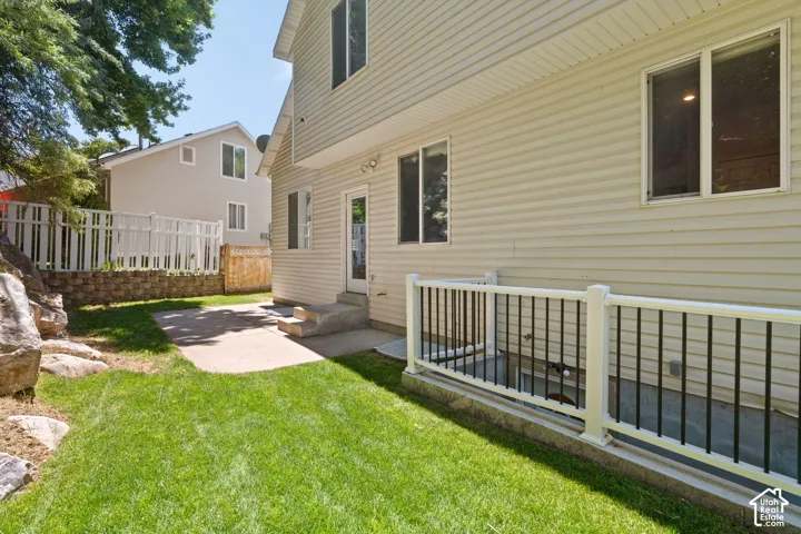 Manicured lawn with a concrete patio and retaining wall