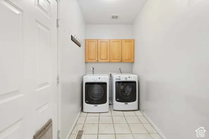 Utility room featuring light wood-finish cabinetry, tile flooring, and a paneled door