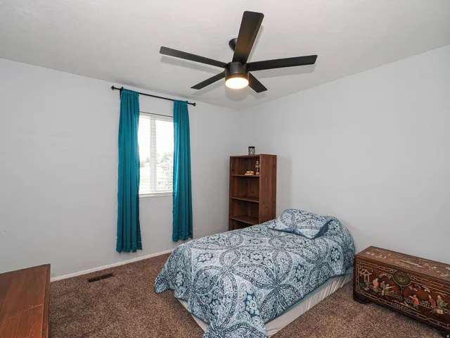 Carpeted room featuring a ceiling fan with integrated lighting, a window with horizontal blinds, and light-toned walls