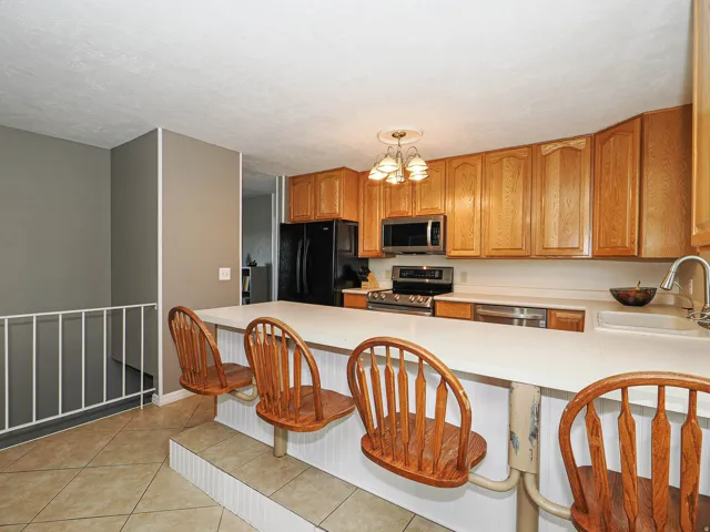 Kitchen featuring light wood cabinetry, stainless steel appliances, and a breakfast bar with built-in seating