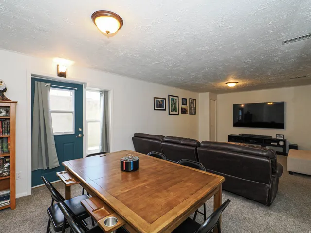 Versatile entertainment space featuring a dedicated dining area, wall-mounted television, recessed lighting, and direct exterior access