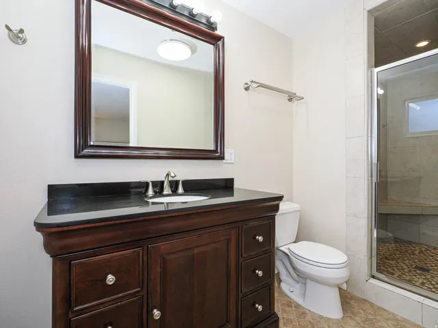 Bathroom featuring a dark wood vanity with a black countertop, an undermount sink, and a brushed nickel faucet