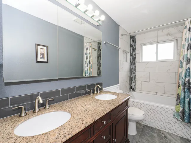 Bathroom featuring a double vanity with granite countertop, undermount sinks, and brushed nickel fixtures