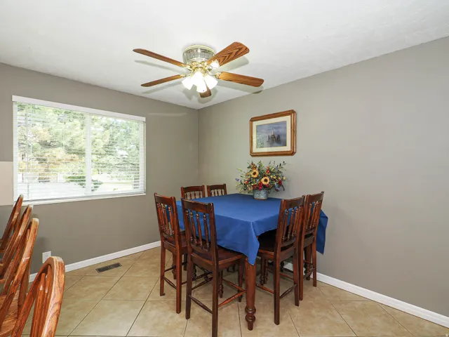 Dining area featuring tile flooring, a large window with blinds, and a ceiling fan with integrated lighting