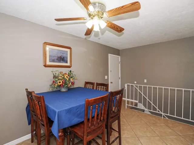 Dining area featuring a wood-finish ceiling fan, neutral wall paint, and tile flooring