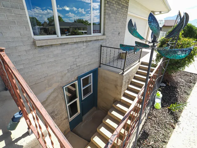 Exterior basement access with concrete steps and wrought iron railings
