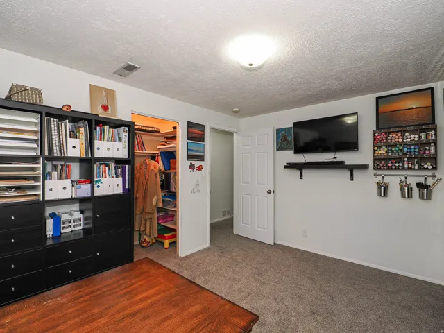Carpeted room featuring a white paneled door and built-in closet with shelving