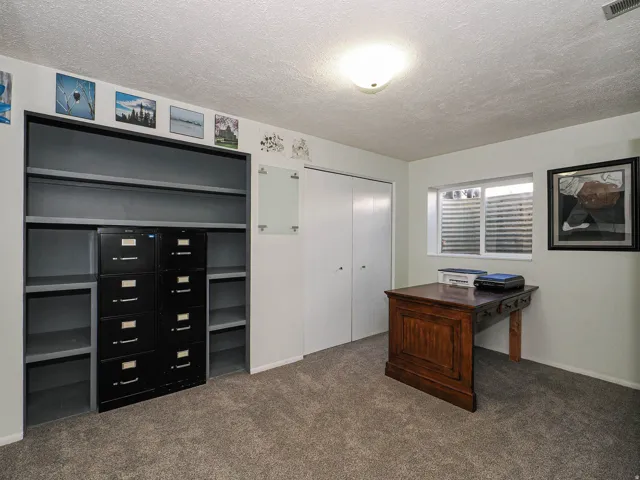 Carpeted room featuring built-in shelving, a recessed window, and white bi-fold closet doors