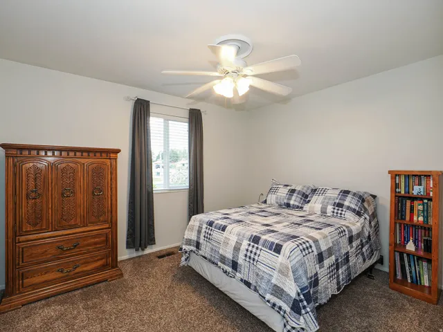Carpeted room featuring a ceiling fan with integrated lighting, a window with blinds, and white walls