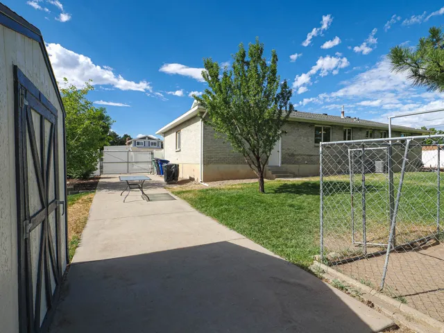 Exterior shed with barn-style doors and a concrete pathway leading to the main residence