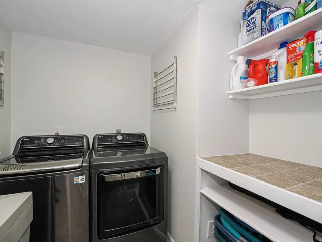 Dedicated laundry area featuring a tile countertop, open shelving, and a wall-mounted drying rack