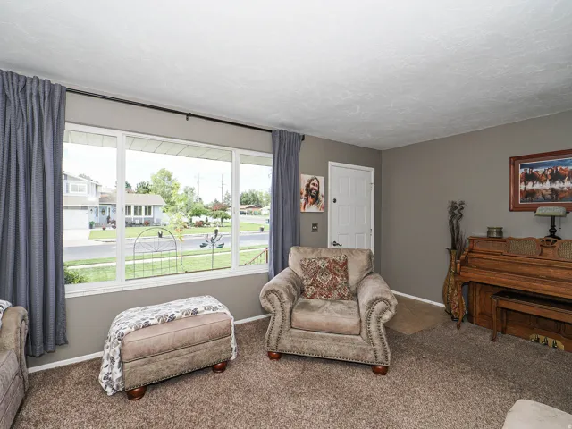 Living area featuring a large picture window with white trim, gray walls, and textured ceilings