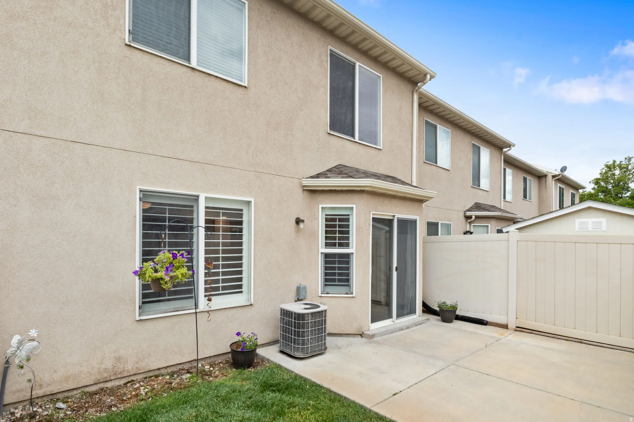 Rear exterior featuring a concrete patio, sliding glass door, and multiple windows