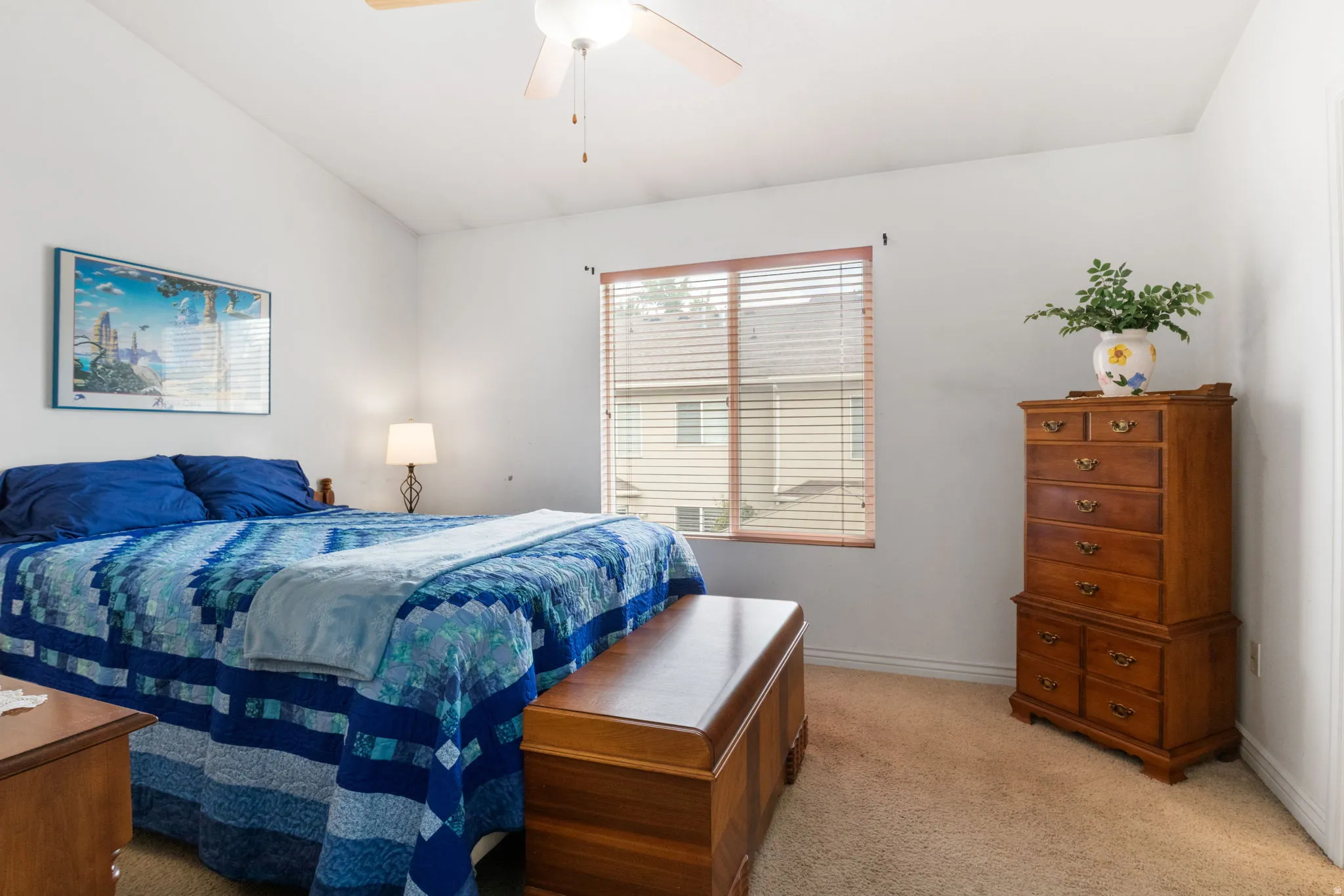 Carpeted room featuring a window with horizontal blinds, a vaulted ceiling, and a ceiling fan with integrated lighting