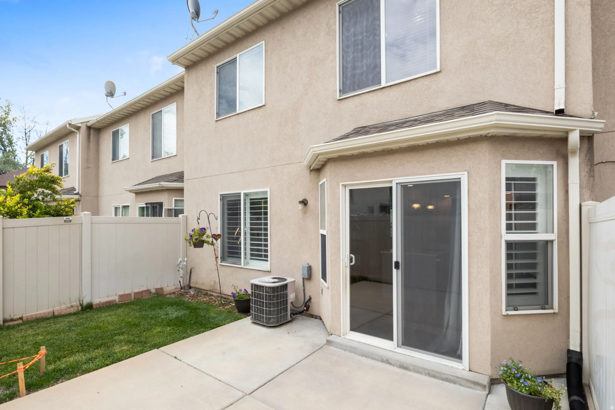 Rear exterior featuring a concrete patio, sliding glass door with screen, and a bay window
