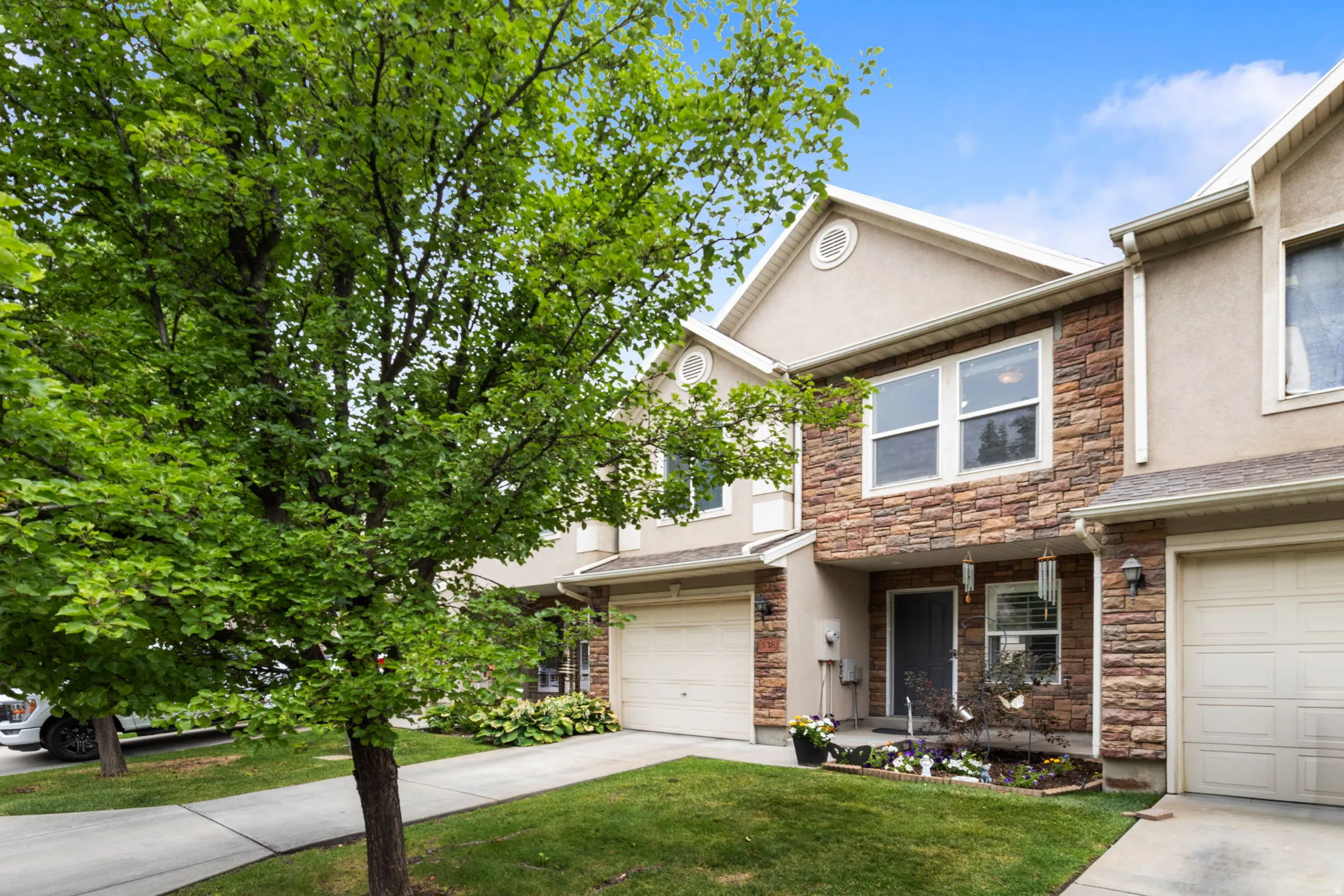 Townhome exterior featuring stacked stone accents and stucco siding
