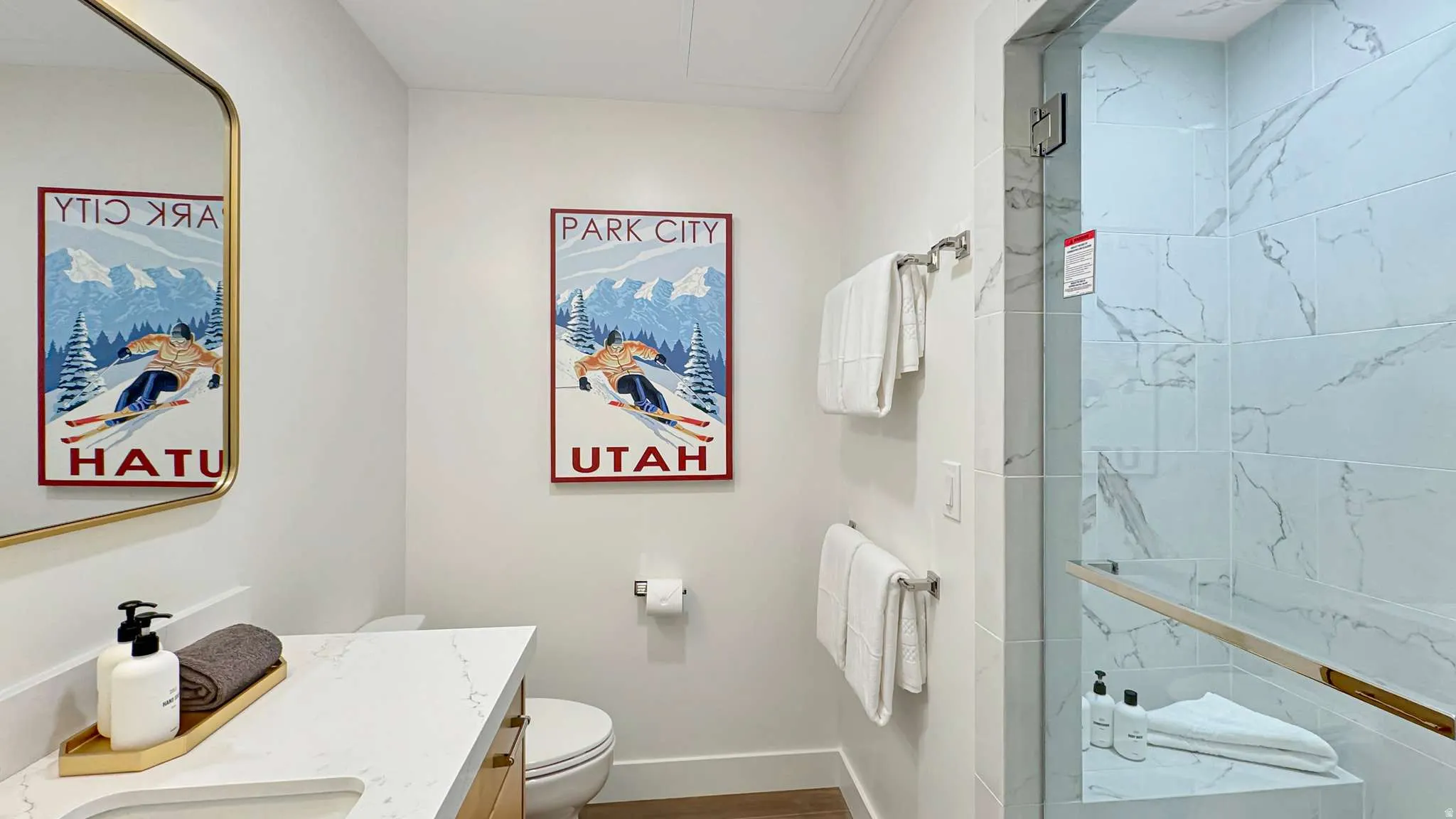Bathroom featuring a walk-in shower with glass enclosure, white marbled tile, a built-in shower bench, and a gold-toned shower handle