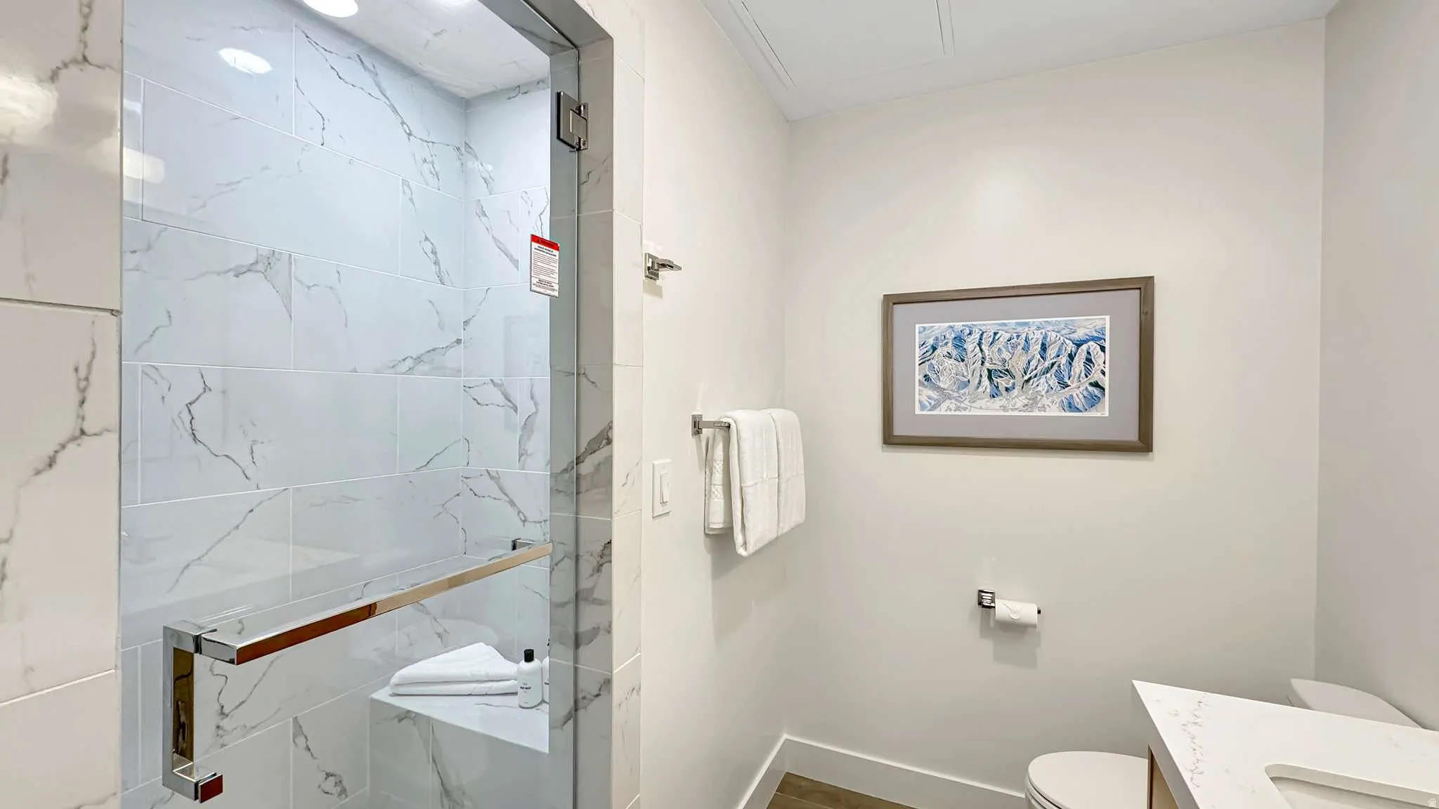 Shower enclosure with clear glass door, chrome hardware, and white marble-look tile