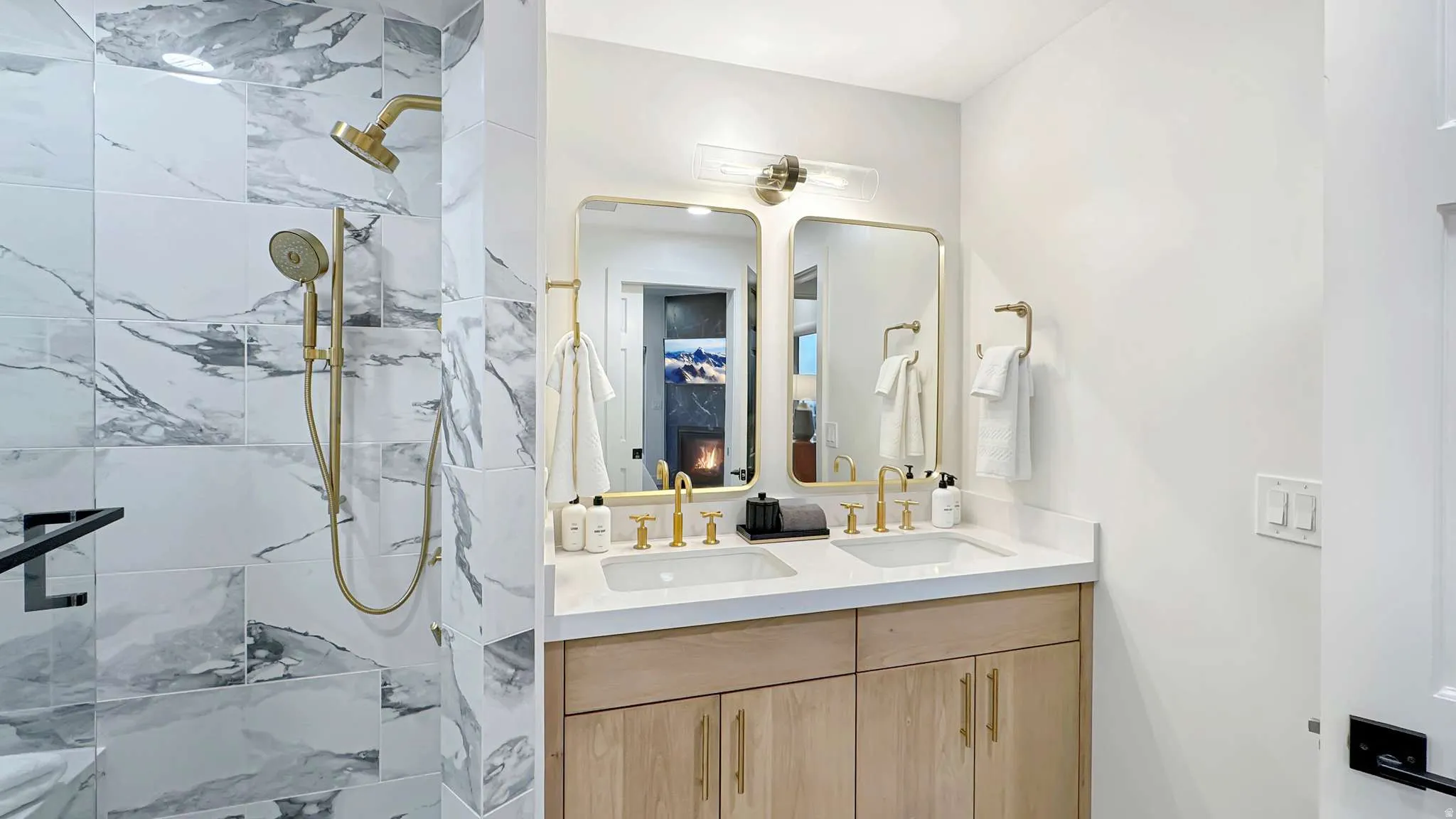Bathroom featuring a double vanity with light wood-finish cabinetry, dual rectangular sinks, and gold-finish fixtures