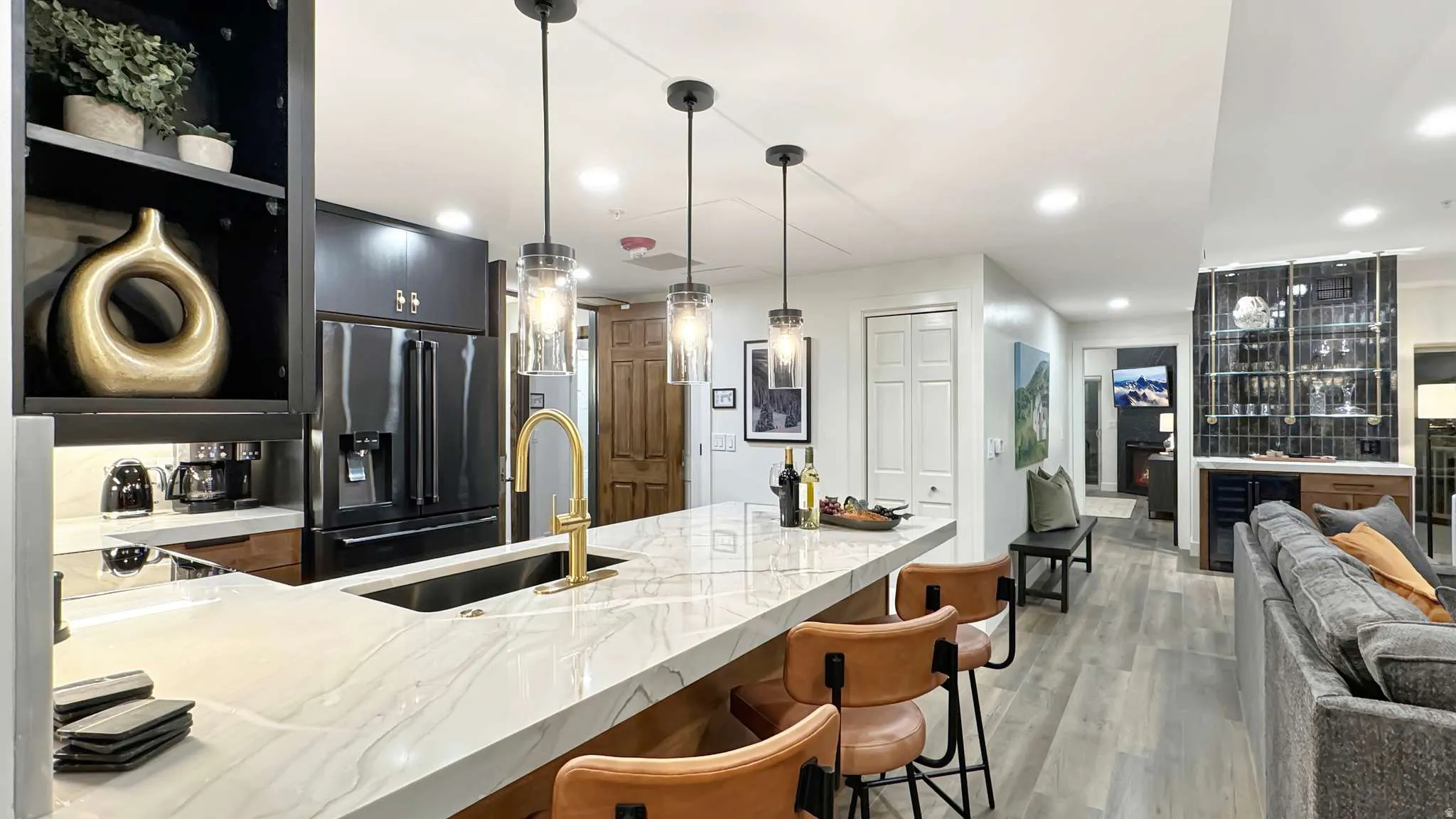 Kitchen island with a white veined countertop, integrated sink, and gold-finish faucet