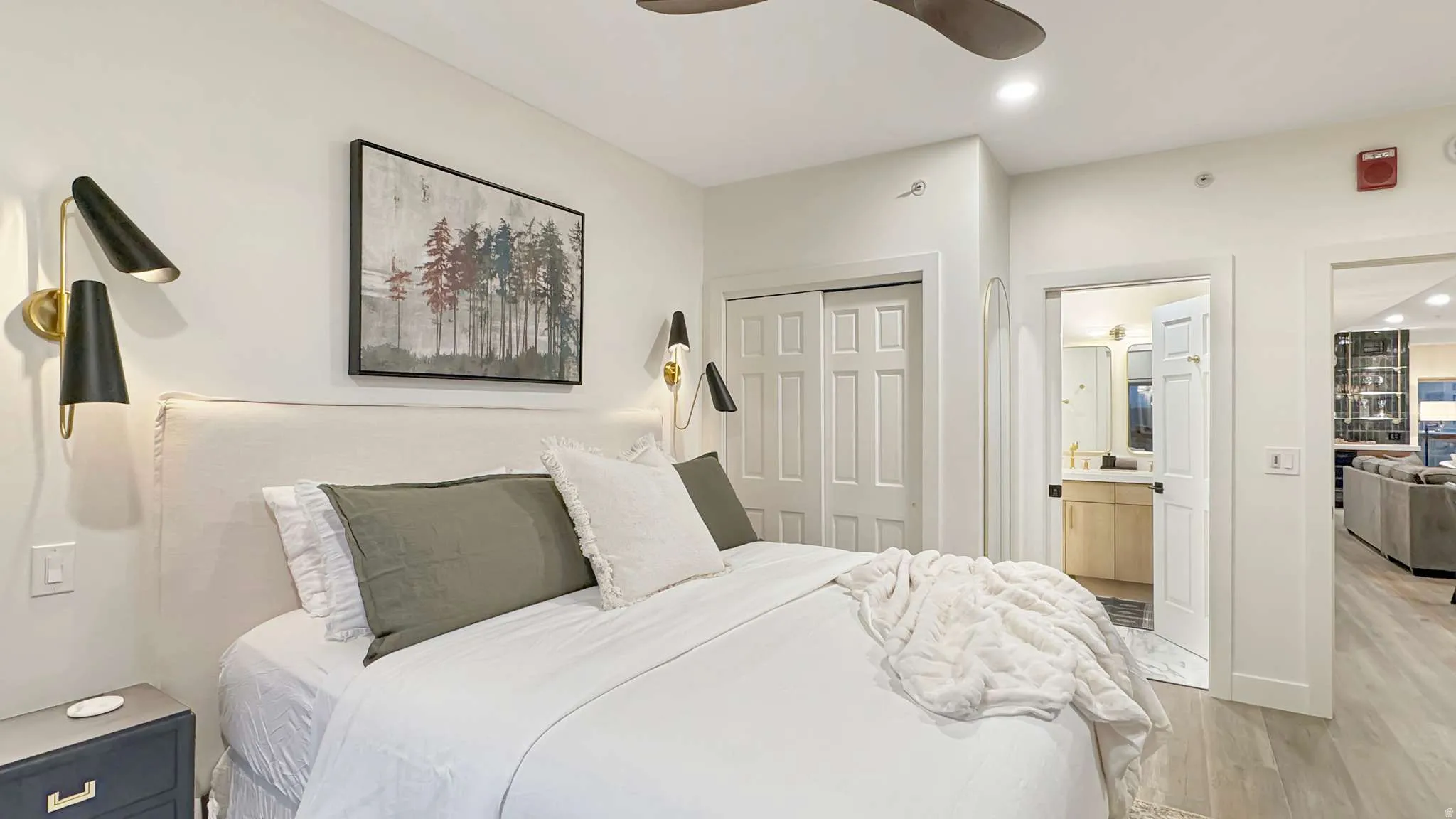 Bedroom featuring a padded headboard, dual wall-mounted sconces, bi-fold closet doors, and wood-finish flooring