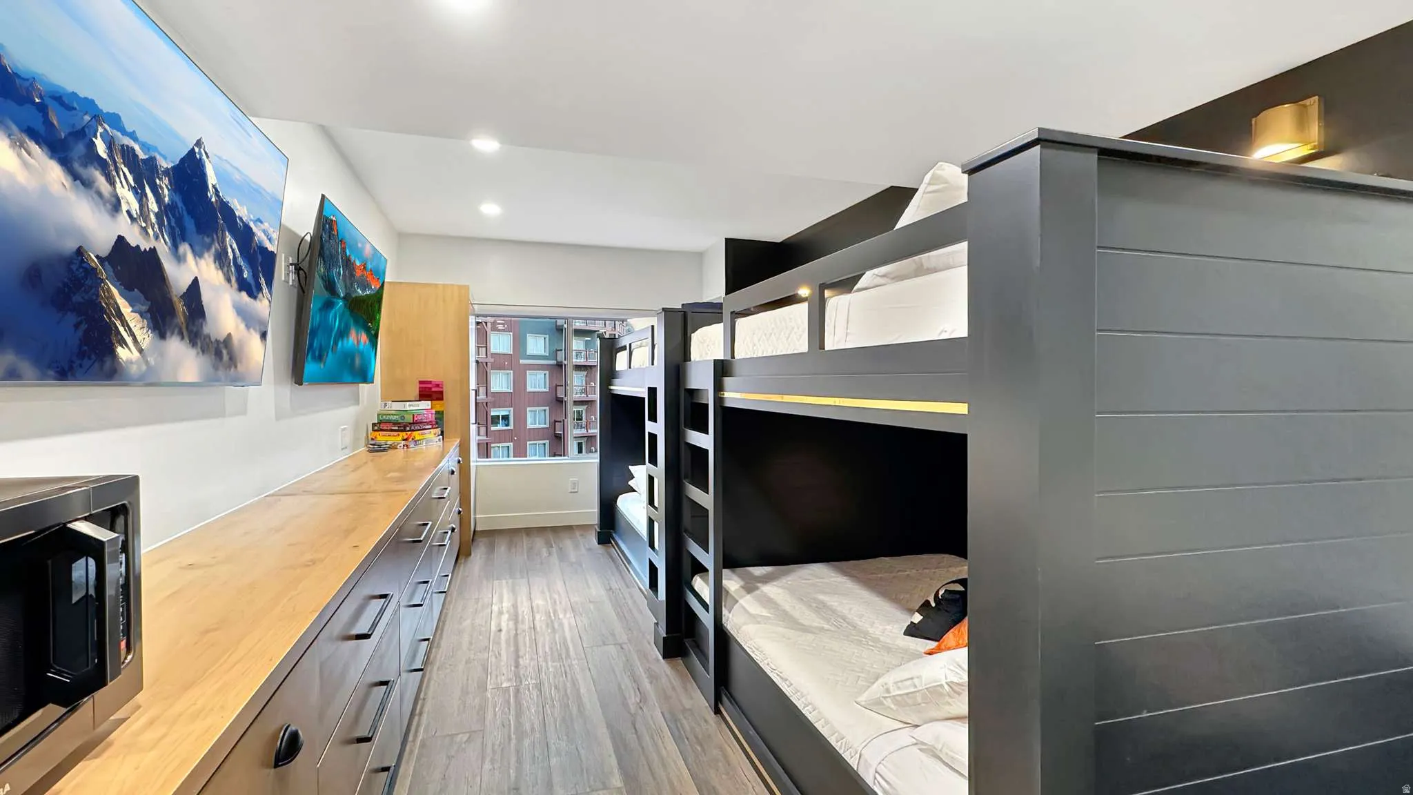 Room featuring wood-finish flooring, recessed lighting, and wall-mounted televisions