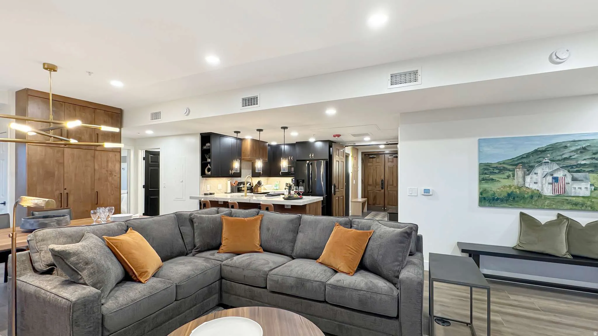 Open-concept living space featuring wood-finish flooring, recessed lighting, and a modern kitchen with dark cabinetry